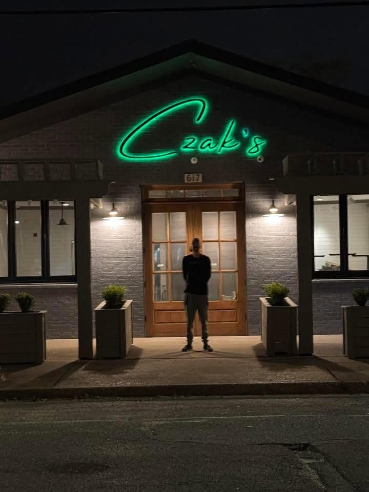 Czak's Coastal Cuisine storefront at night, green neon sign